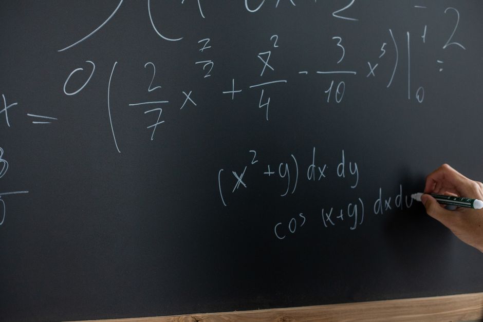 Teacher working through a maths problem on a whiteboard